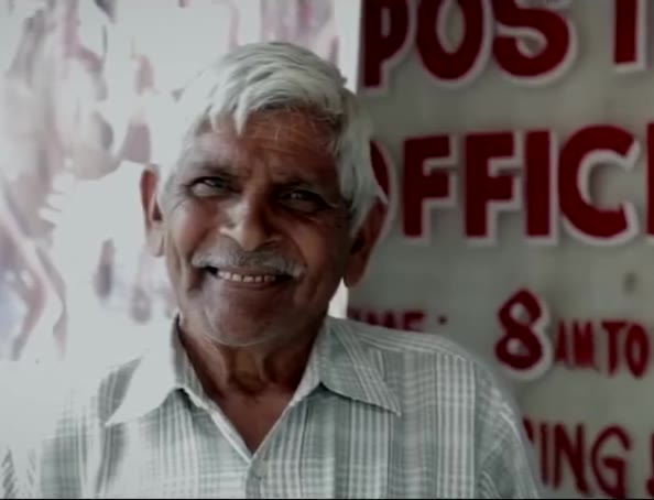 A photo of a man beside a post office sign