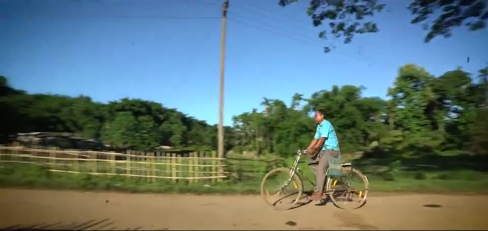 Cyclist on a dirt road beside a bamboo fence